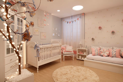 Romântico, aconchegante e lúdico, esse projeto transmite paz, harmonia e bem estar. Como um quarto encantado, os arquitetos Leonardo Velasco e Gabriela Manhães misturaram mobiliário provençal, adornos florais, lambri e papel de parede com luminárias redondas modernas embutidas no teto. O resultado é uma combinação personalizada e contemporânea. Galhos iluminados e pássaros remetem à natureza das fábulas. A iluminação dimerizada proporciona diferentes efeitos cenográficos, economia de energia elétrica e luz indireta para o sono do bebê. Enxoval exclusivo da Jujuba Dorme Bem. Os elementos decorativos foram customizados e reaproveitados pelos próprios arquitetos, como os caixotes pintados de branco usados com mesa lateral.