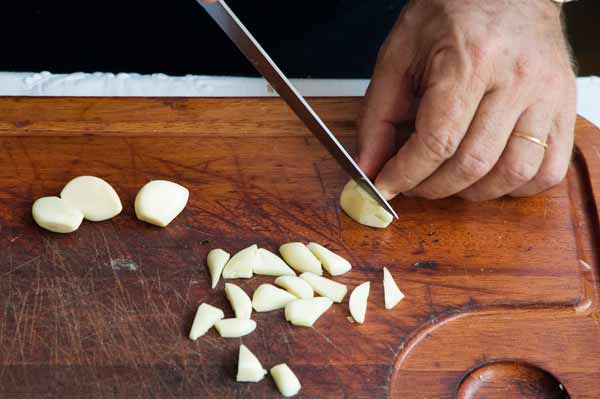 O alho cortado em formato de cunha fica mais f&aacute;cil de cozinhar durante o pre...