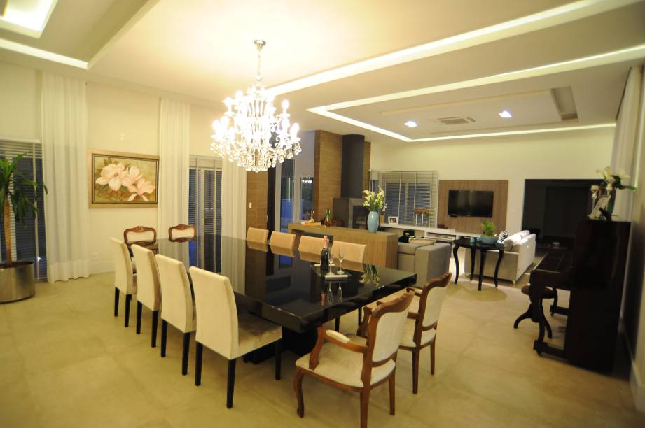 Na sala de jantar integrada ao living, de 80 m², desta casa em Santa Cruz do Sul (RS), o forro e as paredes foram revestidas com gesso acartonado para dar este efeito de iluminação. A mesa é em laca brilhante na cor preta e o piso é porcelanato Portobello. “Foi feito um reforço no gesso para suportar o lustre de cristal que possui 1,20 m de diâmetro”, explicam a decoradora Roberta Kirst e a arquiteta Gabriela Kirst.