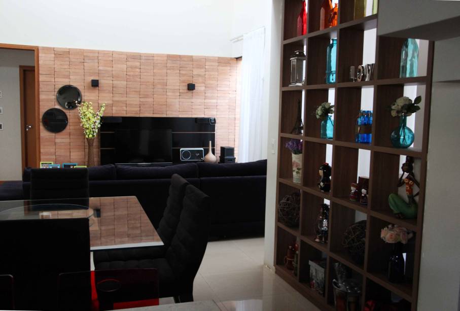 O ambiente, de aproximadamente 40 m², com  sala de estar, jantar e cozinha integrados, teve como ponto de partida para o projeto de interiores o revestimento de tijolo aparente. O material não recebeu nenhum tratamento ou pintura e já havia sido aplicado durante a obra, antes do projeto ser solicitado pela cliente. Laca preta no móvel de TV e acabamento estilo madeira demolição na base da mesa de jantar e mesa de centro destacam o painel de tijolos. O projeto de interiores é de uma residência, em Londrina (PR), e foi assinado pela arquiteta Silvia Cristiane Paurdoski Moreira.