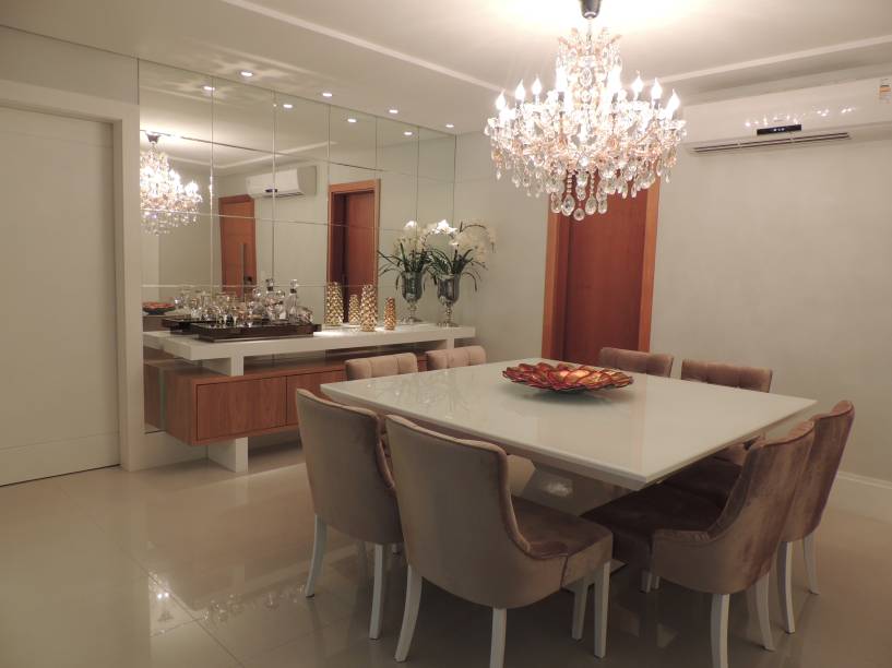 Com a intenção de transmitir elegância, conforto e aconchego, as designers de interiores Carla Bunjes e Simone Serrão optaram por laca branca e bege brilhante no mobiliário. “O espelho cobre uma das paredes para  aumentar a sensação de profundidade”, explicam as profissionais. O espaço de 20 m² foi feito Vila Velha (ES).
