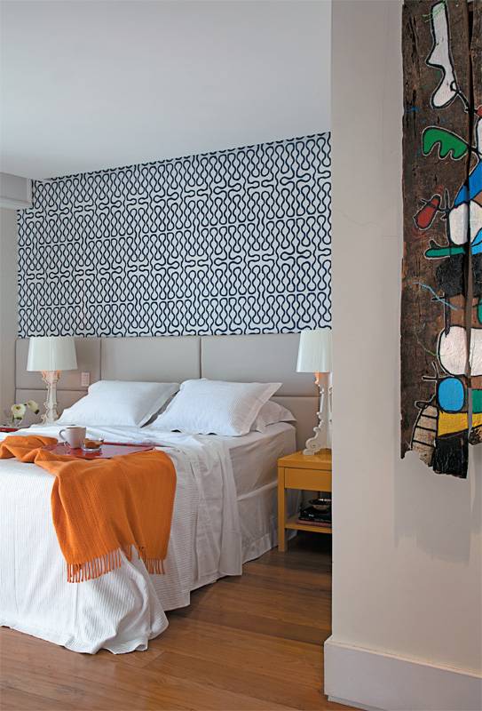 Inspirada pelo tra&ccedil;o contempor&acirc;neo das obras de arte que coleciona, a arquiteta Gisele Taranto resolveu adotar um estilo mais vibrante e colorido na decora&ccedil;&atilde;o deste quarto. Ela sugeriu animar o ambiente com o papel de grafismos azuis criado pela estilista inglesa Vivienne Westwood (Poeira). A laca amarela brilhante mudou a cara das mesas de cabeceira. Abajures da Kartell, roupa de cama branca da Trousseau e manta laranja da Missoni Home (Poeira). Misturar cores, &eacute; claro, tem seu segredo: &ldquo;O essencial para fazer o mix funcionar bem &eacute; n&atilde;o errar na base. Quanto mais neutra, melhor&rdquo;, revela Gisele.