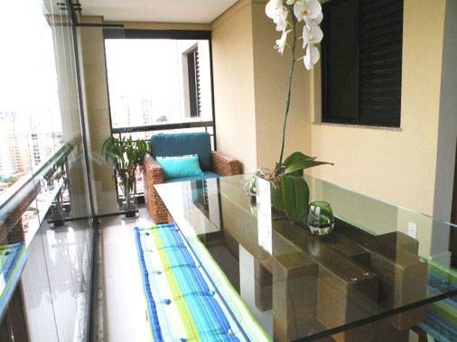 Em 89 m&sup2;, a arquiteta Denise Barbuy montou esta varanda integrada &agrave; sala. Para isso, a profissional nivelou os pisos da varanda e da sala. Assim, a varanda gourmet tornou-se uma extens&atilde;o do estar - ela tem uma mesa para oito pessoas e uma poltrona para leitura ao fundo.