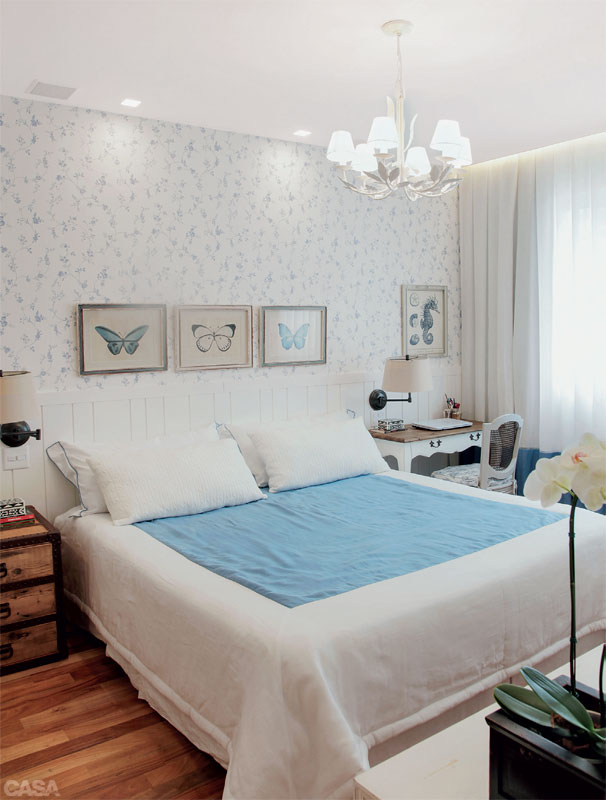 Neste quarto em um apartamento em Copacabana, no lugar de uma cabeceira convencional, é o lambri branco que emoldura a cama e oferece o arremate para o papel de parede estampado de azul e branco (Covering). O visual é de praia romântica, como a moradora queria. Quadros de borboletas da Toute Chose e colcha da Brasil Interiores. Reforma da L+O Arquitetos Associados.