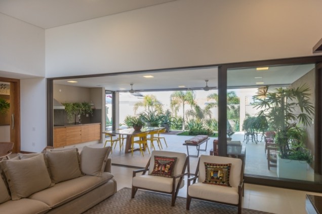 Da sala de estar é possível ver a varanda e o jardim do fundo. Uma única porta ampla integra os ambientes.