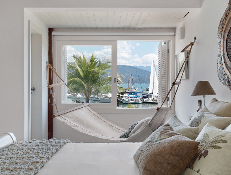 À frente desta casa dentro de uma marina em Parati, um barco ancorado espera pelo jovem casal paulistano. O quarto, acima, incorporou a área de uma pequena varanda. Rede e almofadas de Nani Chinellato, e cama, da Casapronta Quartos. Projeto de Ana Claudia Costa e Bianca Notari.