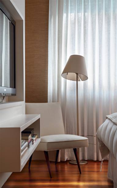 Ainda no quarto, um painel encaixa a TV em frente à cama (marcenaria projetada pela arquiteta Hélia França). Poltrona da Oficina Inglesa e luminária Melampo, da italiana Artemide. Cortina de linho da Oficina 2.Projeto de Roberta Moura, Luciana Mambrini e Paula Faria.