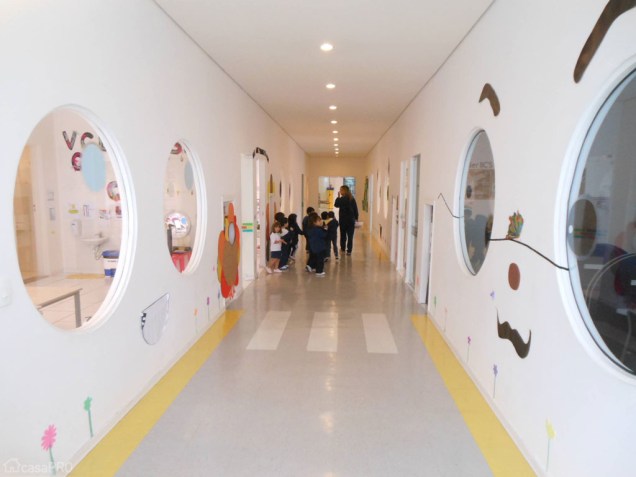 Os corredores desta escola infantil receberam paredes de drywall. Para permitir a visibilidade das salas, foram usados visorese circulares. Projeto do arquiteto Andre Luiz Pereira Pinto.