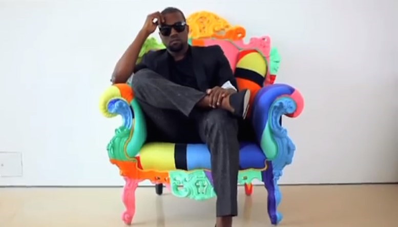 Retrato de Kanye West sentado em uma poltrona de formas clássicas, porém revestida em um mosaico de cores vivas.