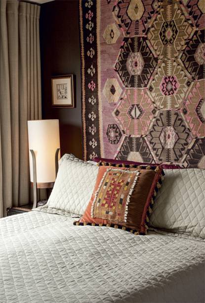 O marrom intenso da parede (Favo de Baunilha*, da Suvinil) traz aconchego ao quarto. Na cama, a almofada assinada pelo designer exibe tecido da tribo indiana banjara. O tapete na parede é um kilim antigo da By Kamy, loja paulistana que Antonio gerencia. projeto do designer Antonio da Motta.
