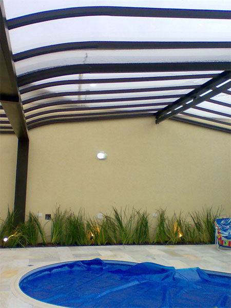 Na área de lazer desta residência, a arquiteta Marcilene Lervolino tinha como desafio deixar a estrutura mais leve possível e ideal para o uso tanto no verão quanto no inverno. Neste trecho da área de lazer tem uma piscina (que foi coberta), área de fitness e sauna. A cobertura foi executada em estrutura metálica na cor cobre e chapas de policarbonato cristal, com movimentação retrátil, para aproveitar os dias de sol. Na área de lazer desta residência, a arquiteta Marcilene Lervolino tinha como desafio deixar a estrutura mais leve possível e ideal para o uso tanto no verão quanto no inverno. Neste trecho da área de lazer tem uma piscina (que foi coberta), área de fitness e sauna. A cobertura foi executada em estrutura metálica na cor cobre e chapas de policarbonato cristal, com movimentação retrátil, para aproveitar os dias de sol.