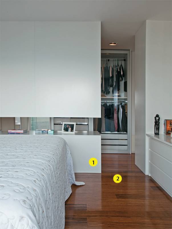 Quarto 1. 1. De madeira laqueada branca, o fundo do arm&aacute;rio (Marcenaria Trettel) divide o quarto do closet. O rasgo de 45 cm de altura entre as partes inferior e superior permite a passagem de luz natural e cria um apoio para objetos. 2. Para o piso, uma op&ccedil;&atilde;o ecol&oacute;gica e f&aacute;cil de instalar: r&eacute;guas de bambu, que s&atilde;o coladas no contrapiso. Da Pau-Pau Pisos de Madeira, as l&acirc;minas aparecem aqui em dois comprimentos (0,90 e 1,85 m), 12,5 cm de largura e 1,5 cm de espessura. J&aacute; v&ecirc;m pigmentadas, tratadas e protegidas com verniz &agrave; base de &aacute;gua.