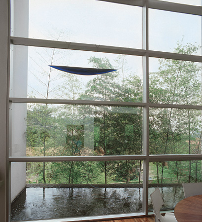 Na sala de jantar, o bambu-moss&ocirc; atr&aacute;s do espelho d&aacute;gua funciona como um...