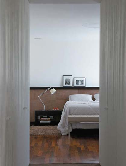Este quarto, num apartamento de 350 m² em Curitiba, passou por uma reforma para se adequar a um casal de jovens proprietários. A cabeceira da cama é de couro natural e aparece em harmonia com o piso de ipê, fornecido pela Formighieri Madeiras.