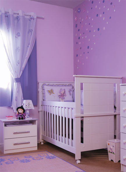 Roxo dá tom de encanto ao quarto. O Berço é da Baby Móveis, protetores do Magazine Demanos e o criado-mudo da Casas Bahia. O tapete e a cortina são da Caçula dos Tecidos, enquanto a lixeira e o abajur foram encontrados em Embu das Artes, SP. A avó fez um arranjo de parede com flores da rua 25 de Março, região de comércio popular em São Paulo. Para colorir o quarto, Nilza misturou tinta látex branca (Suvinil) e corante violeta em bisnaga Xadrez (Lanxess).