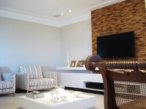 A decoradora Claudia Mattos, de Salvador (BA), procurou dar um ar imponente a esse living. Primeira parte da casa que é vista pelo visitante, o painel é formado por plaquinhas de madeira da Oca Brasil. Dialogam com ele a estampa das poltronas, próprias para duas pessoas.