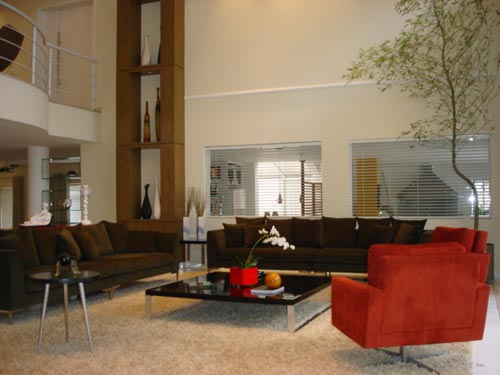 Nessa segunda parte do living de Sueli Porwjan, as poltronas vermelhas fazem conjunto com os sofás em café. A decoradora procurou agradar o casal dono da casa, ao utilizar tons sóbrios (preferidos dele) e quentes (favoritos dela).