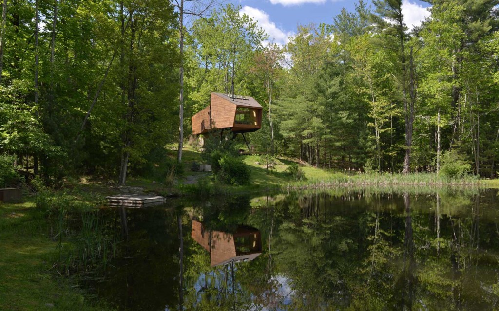 casa de madeira com um lago em uma floresta