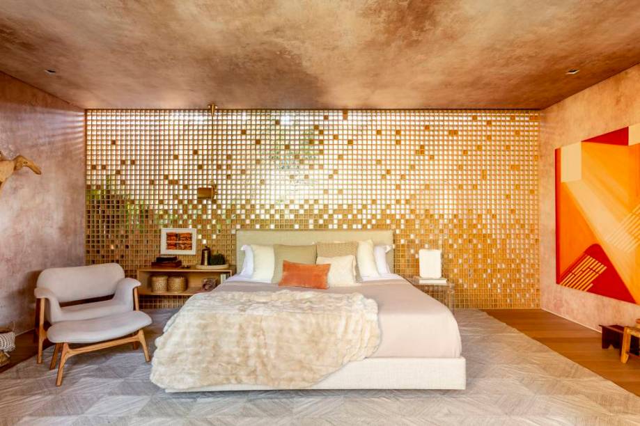 Neste quarto criado pelo escritório Suite Arquitetos, na CASACOR São Paulo, o painel de muxarabi feito de carvalho americano parece que se dissolve à medida que os pequenos quadradinhos vão revelando a área aberta da parte de fora do espaço. O criado-mudo feito da mesma madeira está preso à parede e a cabeceira é uma grande almofada revestida de linho.