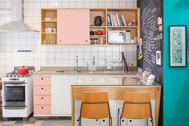 No apartamento de uma ilustradora em São Paulo, as arquitetas Claudia Bresciani e Júlia Risi desenharam uma cozinha descolada, que conta com armários de pinho com portas brancas e rosa, além de uma parede lousa.