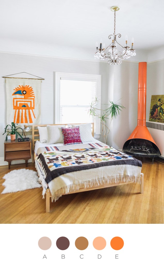 Os tons terrosos dominam este quarto, que conta com lareira laranja e roupa de cama estampada.