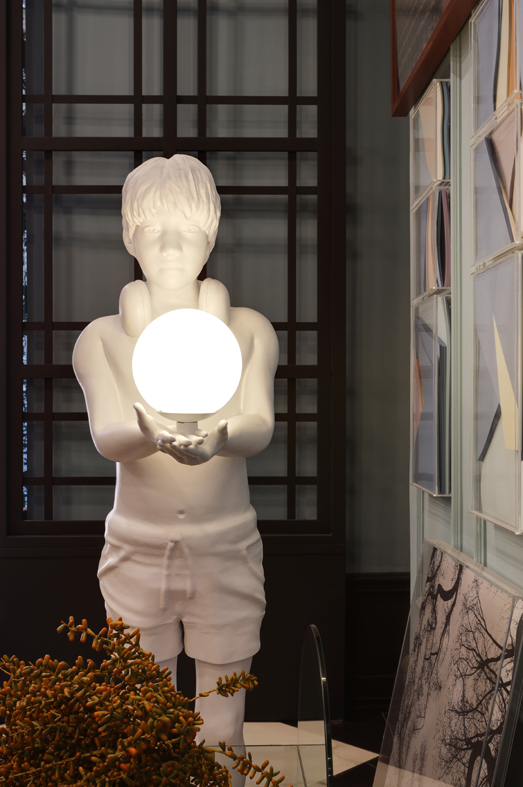 No ambiente <strong>Foyer Bienvenue</strong>, do arquiteto Lisandro Piloni, a estátua humana <em>Uma Eterna Criança</em> faz parte de uma série de luminárias numeradas e criadas em parceria com a DS contemporânea e o designer Samuel Angelo.