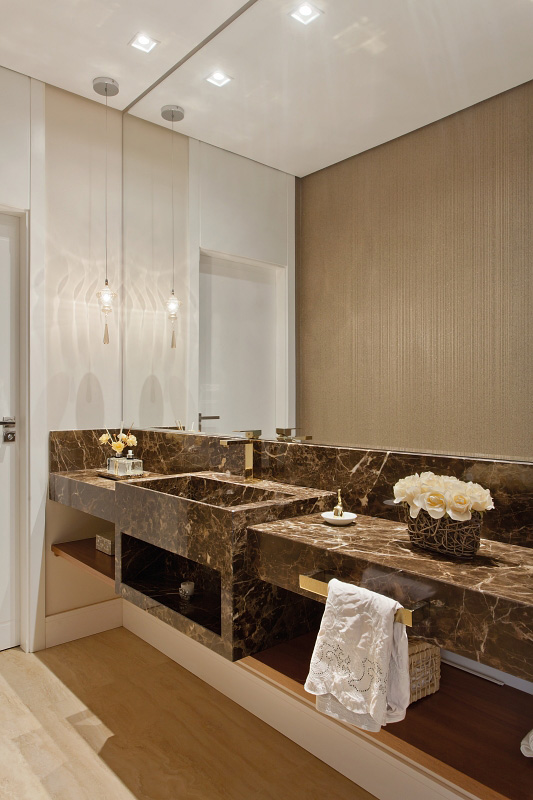 No lavabo, o espelho acompanha toda a extensão da bancada em mármore marrom imperador e duplica a delicadeza do papel de parede. No lavabo, o espelho acompanha toda a extensão da bancada em mármore marrom imperador e duplica a delicadeza do papel de parede.