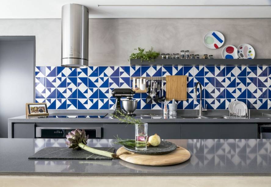 O azul e o branco do painel casam direitinho com o pínus dos armários e com o cinza utilizado no piso, nas paredes e nas bancadas de composto sintético. Projeto assinado pela arquiteta Ana Luiza Almeida Prado Sawaia