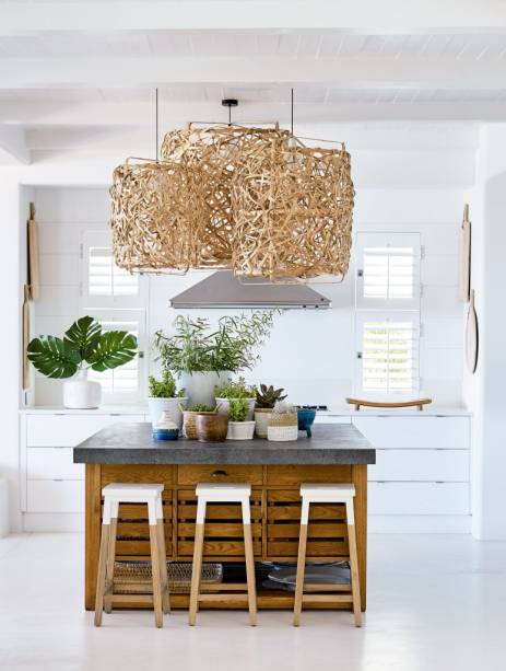 Esta proposta, na África do Sul, traz boas ideias para cozinhas abertas: vasos disfarçam o cooktop e pendentes escondem a coifa. As plantas e os materiais naturais ainda trazem um ar fresh para o décor. A madeira quebra a assepsia do branco e adiciona calor. Projeto de Kim Stephen