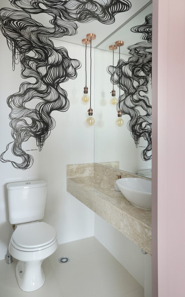 No lavabo, existem três elementos que criam uma composição completamente contemporânea e urban: a wall art que inicia no forro de gesso e encerra na parede, a porta rosa matte e as duas lâmpadas de filamento de carbono pendentes.