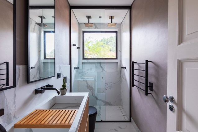 Para o banheiro os profissionais optaram por seixos pretos e piso de porcelanato imitando madeira.