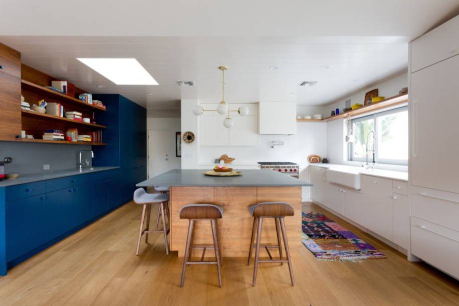 A cozinha desta casa em Los Angeles possui dois tons: de um lado é essencialmente branca e, do outro, azul. A transição entre uma extremidade e outra é mediada pelo calor da ilha de madeira, mesmo material do usado no piso. O teto ripado também funciona como elemento decorativo neste projeto assinado por Natalie Myers do escritório Veneer Designs