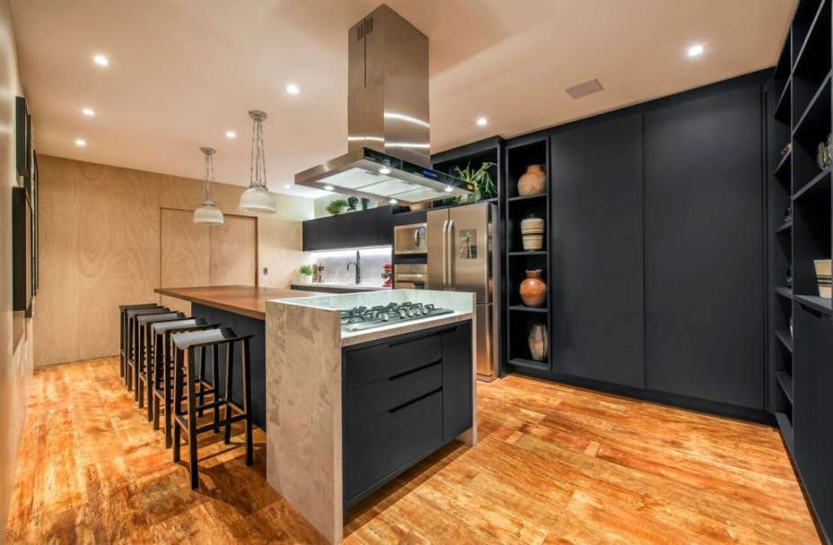 O preto é o grande destaque desta cozinha. O tom surge nos armários e na bancada, sempre com acabamento fosco. Madeira e mármore completam a decoração. O projeto do arquiteto Carlos Navero