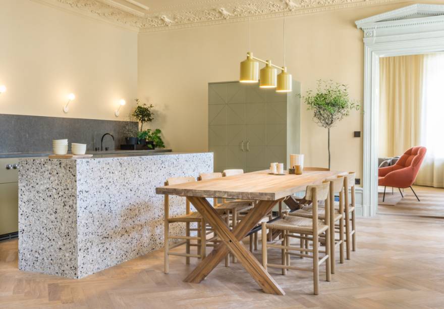 Na reforma desta cozinha, os adornos neoclássico foram mantidos, mas ganharam um belo toque de modernidade cobertos por tons pastel. O mobiliário em madeira e a bancada em granito contribuem para a atmosfera descontraída. O projeto foi concebido pelo Note Design Studio