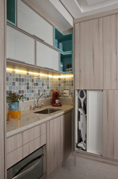 Nenhum centímetro da cozinha foi desperdiçado neste projeto,  a marcenaria sob medida é a grande responsável pelo feito. Aproveitando das paredes até o teto, ela possibilita a melhor utilização possível do espaço. Os tons claros na ambientação contribuem para aumentar a sensação de amplitude. O projeto é do escritório Andrade & Mello Arquitetura