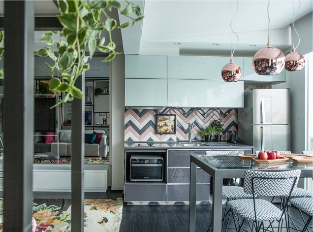O revestimento em chevron nos tons rosa, cinza e branco trouxe personalidade para a pequena cozinha. Os armários com acabamento brilhante completa a ambientação com estilo. O projeto é do escritório Andrade & Mello Arquitetura