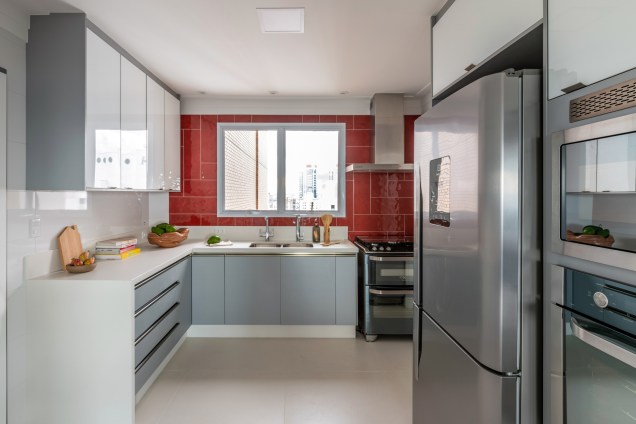 Na cozinha, a arquiteta adicionou um toque de cor com o revestimento vermelho na parede acima da bancada. Na cozinha, a arquiteta adicionou um toque de cor com o revestimento vermelho na parede acima da bancada.