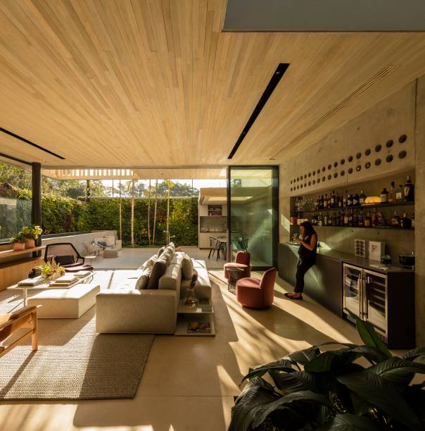 A cozinha, integrada na maior parte do tempo, possui portas que correm por um trilho e a isolam completamente em dias de eventos. Já a iluminação é projetada por um forro tensionado em cima da bancada. A cozinha, integrada na maior parte do tempo, possui portas que correm por um trilho e a isolam completamente em dias de eventos. Já a iluminação é projetada por um forro tensionado em cima da bancada.