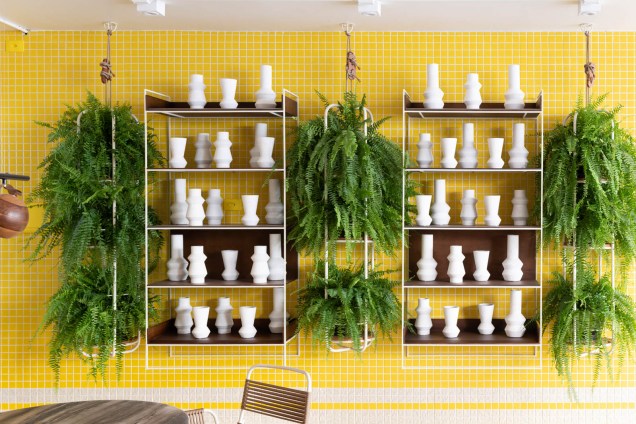 Na <strong>Varanda Palm Springs</strong>, o arquiteto Jean de Just instalou uma estante moderna que salta da parede colorida em verde e amarelo, dando o toque de brasilidade proposto para o ambiente.