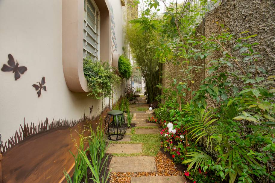 Jardim dos Pés Descalços – Neide Braga. O espaço buscou uma nova leitura no ambiente com a repaginação dos pisos de cimentos já existentes. As vegetações foram mantidas e revigoradas. Houve introdução de elementos novos como plantas em tons alegres, esculturas, pedras, banco e iluminação com linguagens que remetem ao descanso e bem-estar. Como solução criativa, a paisagista optou por pinturas artísticas de troncos de árvores, que escondem as fissuras nas paredes. Destaque também para os objetos decorativos e funcionais de serralheria artística feitos por<span> </span>uma instituição que trabalha com projetos sociais para pessoas com transtorno mental<span> </span>e para as luminárias de lua, confeccionadas feitas pela equipe da profissional com globos de polietileno e pintadas a mão. Um ambiente bonito com elementos de baixo custo e baixa manutenção, facilmente aplicável para uma casa.