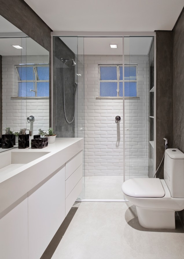 No banheiro social, o branco se repete em diversos elementos. Os tijolinhos do box garantem o charme do ambiente, enquanto o concreto das paredes dá uma sensação de sobriedade.