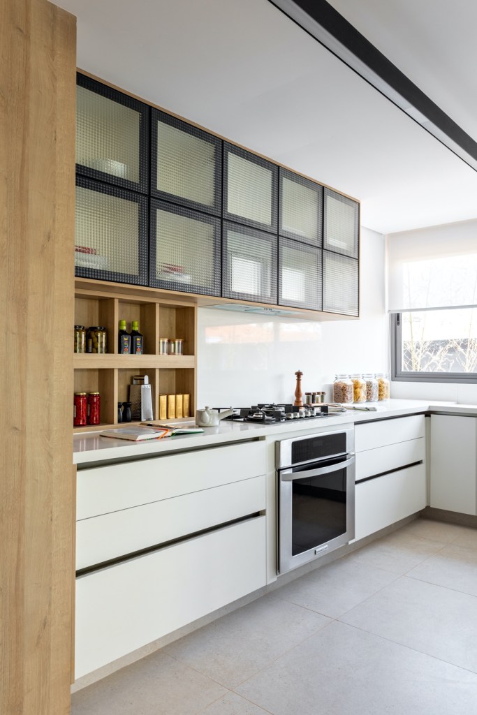 Cozinha integrada; bancada branca; armário com porta de vidro