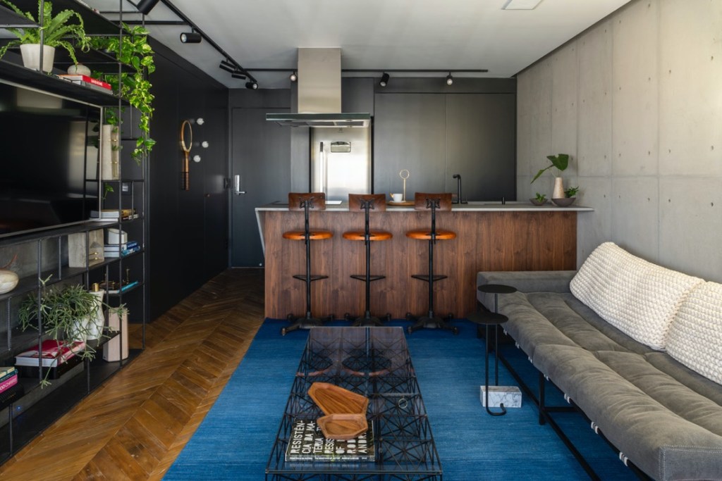 Cozinha integrada; cozinha americana; piso de taco; tapete azul; sala de estar integrada; bancada de madeira; parede preta