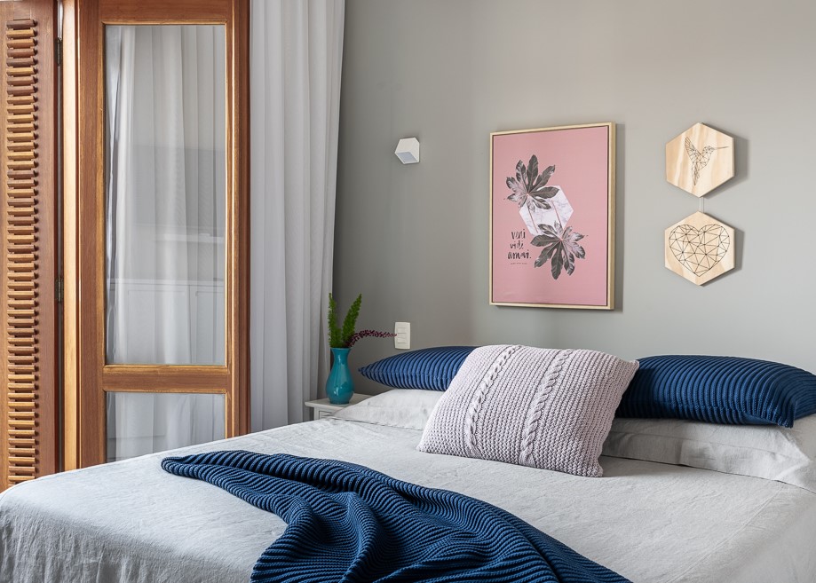 Quarto com parede cinza; cama; roupa de cama; manta azul marinho; quadro; travesseiros