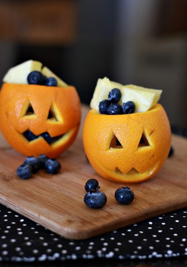 Laranja cortada em formato de abóbora e com blueberries e pedaços de abacaxi dentro