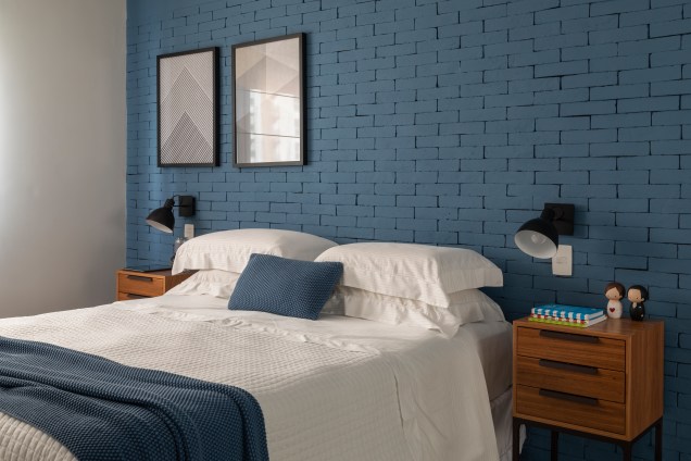 Na parede principal do dormitório, os tijolinhos pintados no tom azul. Nos móveis laterais, a miniatura do Batman, à esquerda, é figurante perante os bonecos do casal, do lado esquerdo