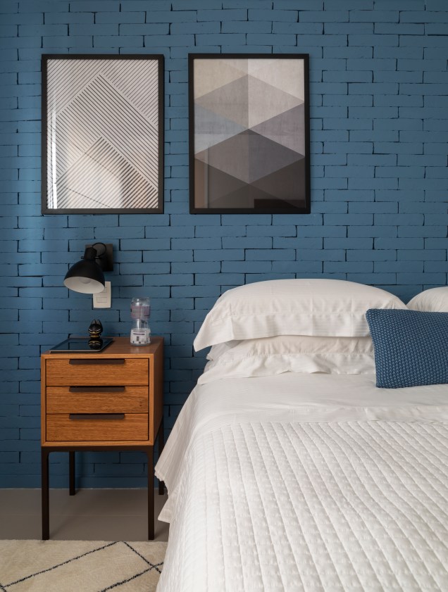 Na parede principal do dormitório, os tijolinhos pintados no tom azul. Nos móveis laterais, a miniatura do Batman, à esquerda, é figurante perante os bonecos do casal, do lado esquerdo