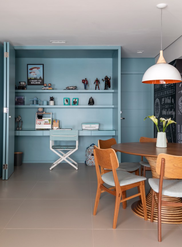 Quando fechado, o escritório desaparece, dando lugar a um bonito painel azul, no formato de porta camarão, na sala de estar