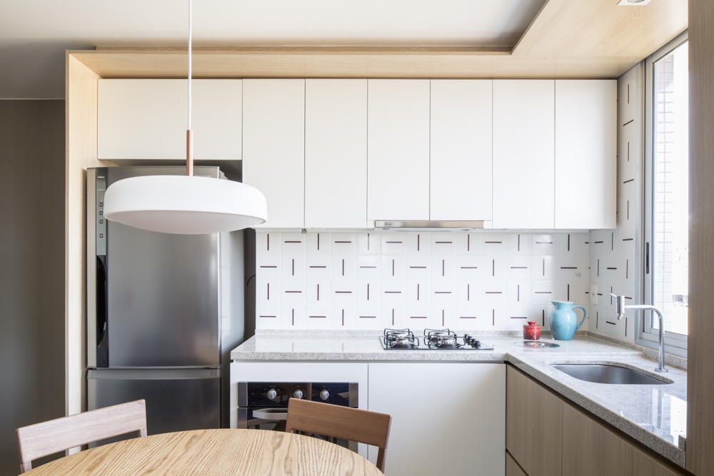 cozinha com armários brancos e azulejos estampados em apartamento pequeno