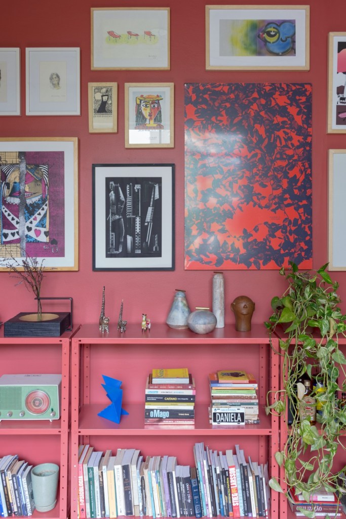 sala com parede pintada de rosa e repleta de quadros